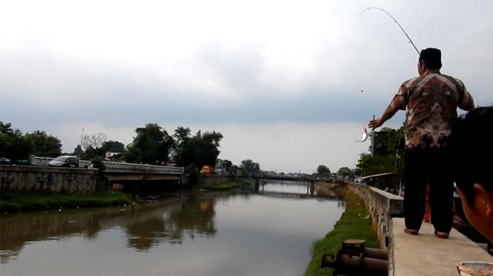 Seorang warga mendapat ikan dari memancing jelang sore di sebelah Stasiun Pompa RW 04 Kembangan Utara. (Foto: Gapey Sandy)