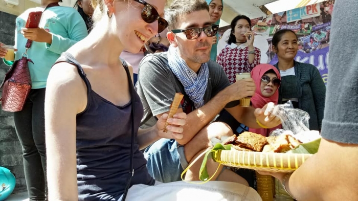 Sepasang bule Prancis yang mampir ke Indonesia Community Day (ICD) 2017 di Plaza Pasar Ngasem, juga menyempatkan diri nyeruput jamu plus kunyah-kunyah tempe bacem yang disuguhkan Tamita Wibisono. Salah satu sisi suasana Jogja dengan lintas bangsa. Foto: Rahab Ganendra