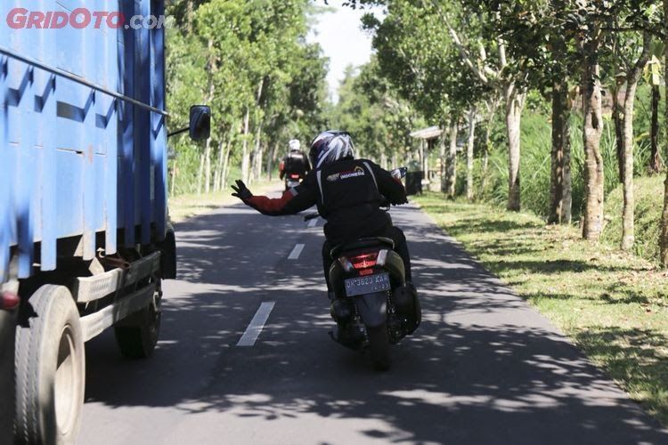 Tampak pemotor sedang menyalip truk sembari merentangkan tangannya (sumber: gridoto.com)