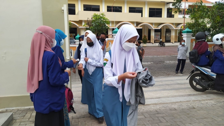 Gambar 1. Kelompok KKN AsMeT UM sedang membantu pelaksanaan kegiatan rutin pelayanan COVID-19 di SMA Negeri 10 Malang
