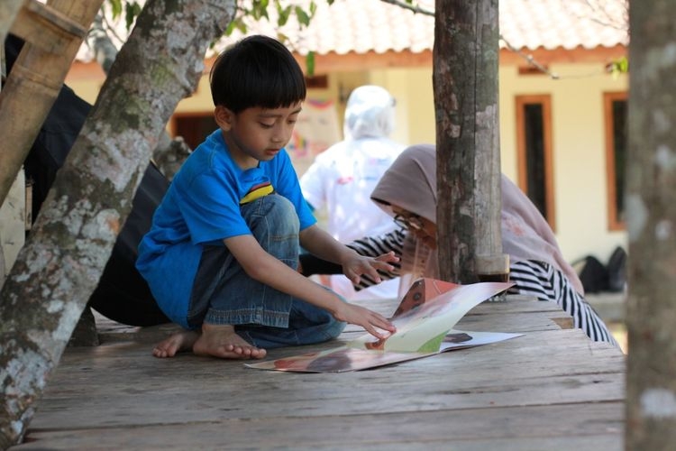 Seorang anak dari kecamatan Cigeulis sedang membaca buku cerita anak-anak di Taman Bacaan Masyarakat (TBM) Saung Huma.(DOK. PRIBADI/GABRIELLE ALICIA WYNNE PRIBADI)