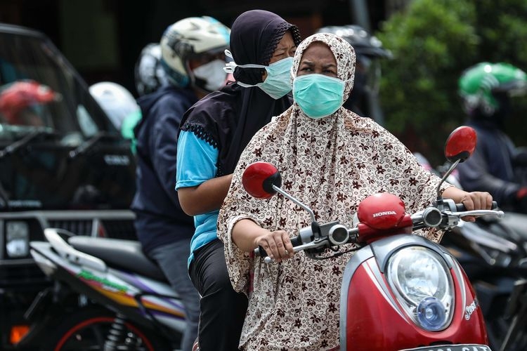 Warga menggunakan masker saat mengendarai sepeda motor di kawasan Mampang Prapatan, Jakarta Selatan, Senin (6/4/2020).(KOMPAS.com/GARRY LOTULUNG)