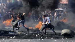 Pengunjuk rasa Palestina menghadapi pasukan Israel di pos pemeriksaan Hawara, selatan Kota Nablus, Tepi Barat, Palestina. (JAAFAR ASHTIYEH/AFP)