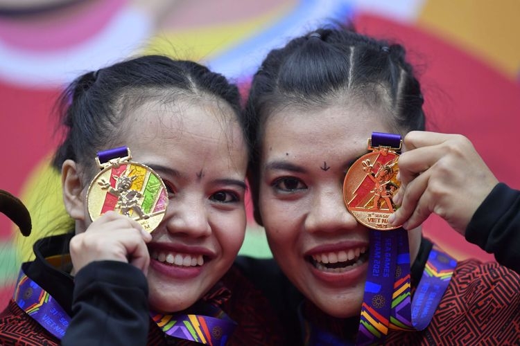 Pesilat Indonesia Riska Hermawan (kiri) dan Ririn Rinasih (kanan) berpose dengan medali emasnya yang diraih pada final Seni Ganda Putri Pencak Silat SEA Games 2021 (ANTARA FOTO/ZABUR KARURU)