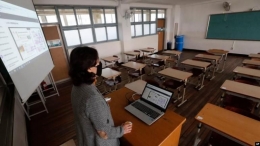 Ilustrasi guru mengajar kelas online di tengah wabah corona di sekolah (via voaindonesia.com)