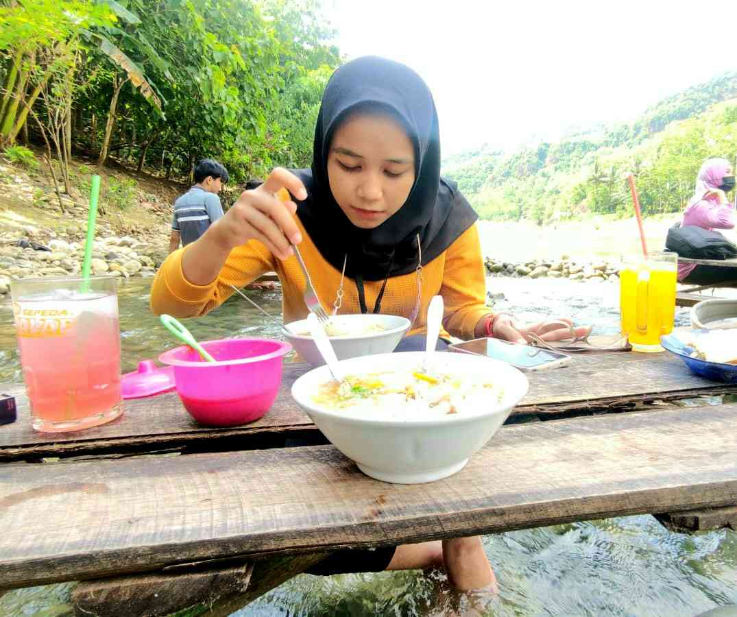 Pengunjung menikmati makanan di atas aliran sungai di Kediri
