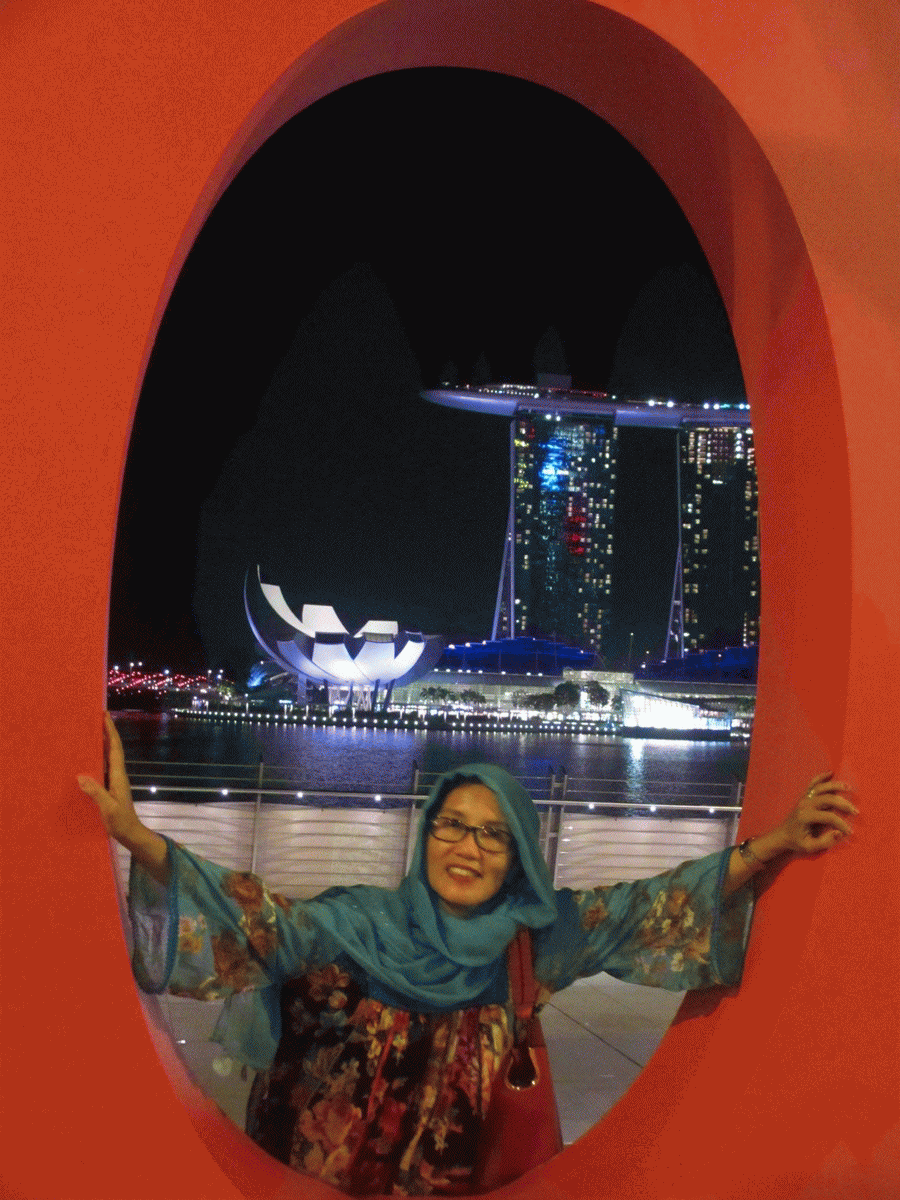 (My Wife: Ny. Farida Rendra Ariani, berpose di antara horiizon huruf O, Gedung Esplanade cantik di waktu malam dan Laut Marina Bay / Photo by: Rendra Tris Surya)