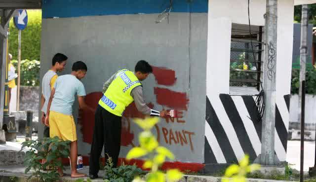 Tersedianya ruang publik untuk kaum muda akan mencegah munculnya graffiti liar. Dua orang pemuda diminta untuk membersihkan graffiti di pos polisi Jogjakarta(Foto : R. Wibisono/Solo Pos).