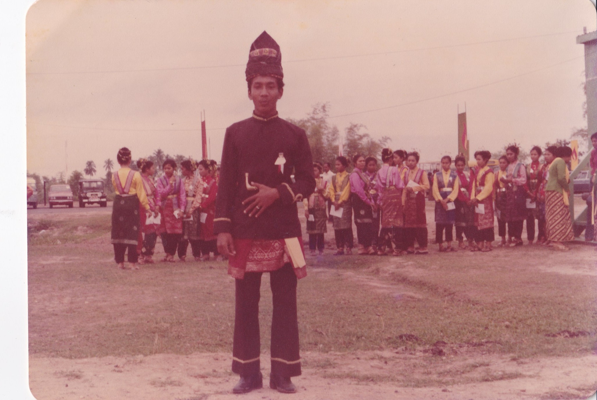 (Keterangan Photo: Penulis, yang di tahun 1978 bersiap-siap menyambut Pak Harto di Lapangan Terbang Malikussaleh, Lhokseumawe sejak jam 7 pagi. Sambil beberapa kali latihan pemanasan untuk pemantapan skenario. Di latar belakang, para penari wanita anak-anak SMA yang terpilih dari seantero Kota Lhokseumawe tersebut, juga sedang bersiap-siap menunggu datangnya pesawat Presiden Soeharto...dan akan melalukan tarian tersendiri  / Photo: Dok Pribadi)