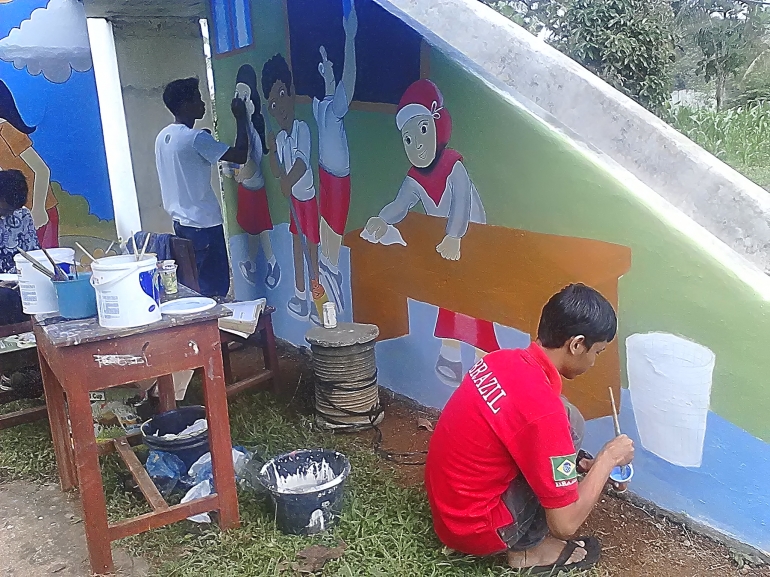 Dua siswa SLB N Metro tengah melukis di sebuah tempat bermain anak-anak ABK. (doc. pribadi)