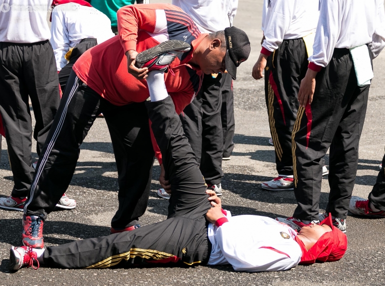 Pelatih menolong darah dagingnya yang otot kakinya tegang