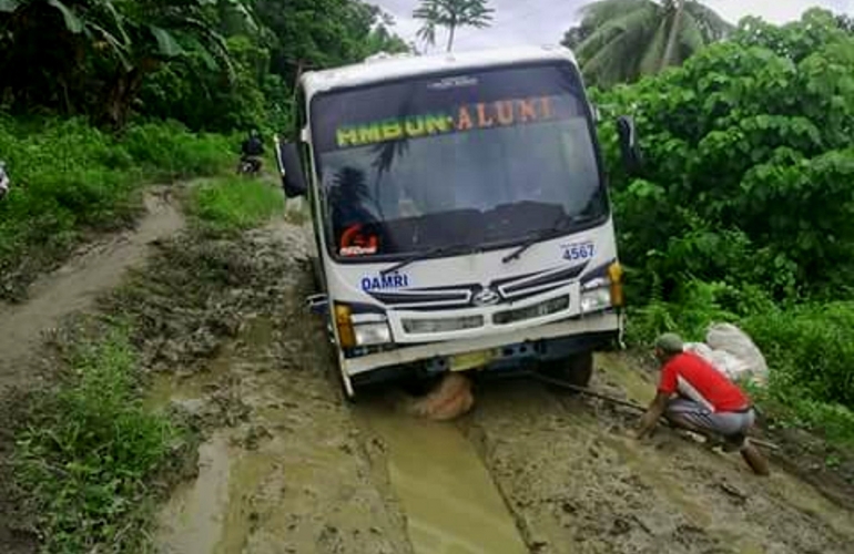 Seorang warga sedang memperbaikan Bus Damri akibat rusaknya jalan yang dilewati