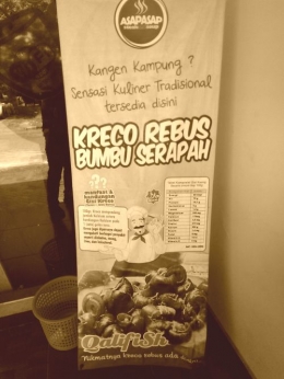 ada banner promosi kreco (sejenis siput air) makanan terkenal di Jawa Timur, terletak sebelum pintu masuk