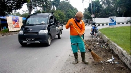 Petugas kebersihan menyapu sampah-sampah yang dibuang sembarangan di pinggir Jalan Raya Pajajaran, Pamulang, Tangsel. (Foto: Gapey Sandy)