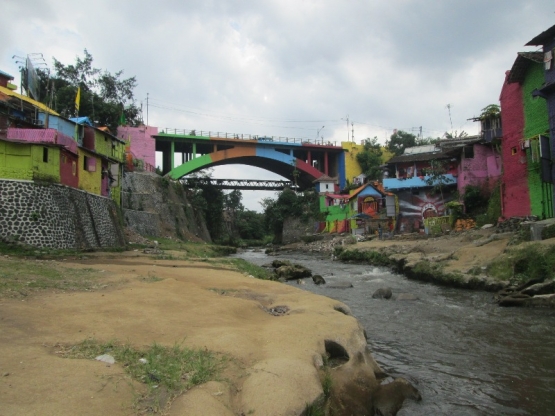 DUA KAMPUNG. Sisi kiri sungai Brantas adalah Kampung Warna Warni Jodipan (KWJ), sisi kanannya adalah Kampung Tridi Kesatrian yang menyusul kesuksesan KWJ. Tampak pula jembatan yang di cat warna warni untuk menyelaraskan kedua kampung. Dok pribadi