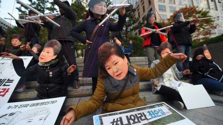 Demonstran mengenakan topeng presiden Korea Selatan dan sahabatnya Choi Soon sebagai bentuk protes skandal nepotisme. Source: CNN