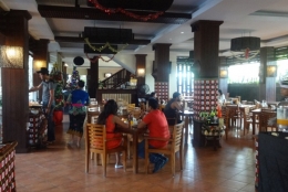 Suasana Chill In Restaurant dengan aksen kayu pada meja dan kursi dan kain poleng yang membuat cita rasa Bali