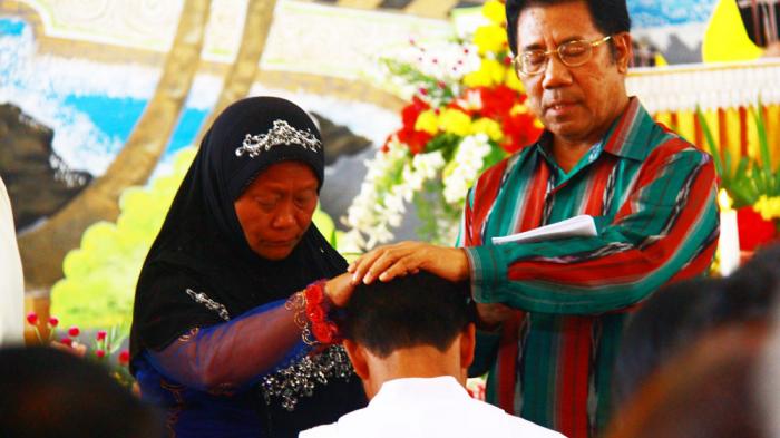 Momen saat Siti Asiyah dan ayah angkat menumpangkan tangan ke kepala P.Yanto di upacara tahbisan imam, di Maumere, Flores, 10 Oktober 2015. Pos Kupang/Feliks Janggu