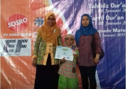 Naura (tengah) menunjukkan medali dan sertifikat juaranya dengan diapit Ibu dan Ustadzahnya.