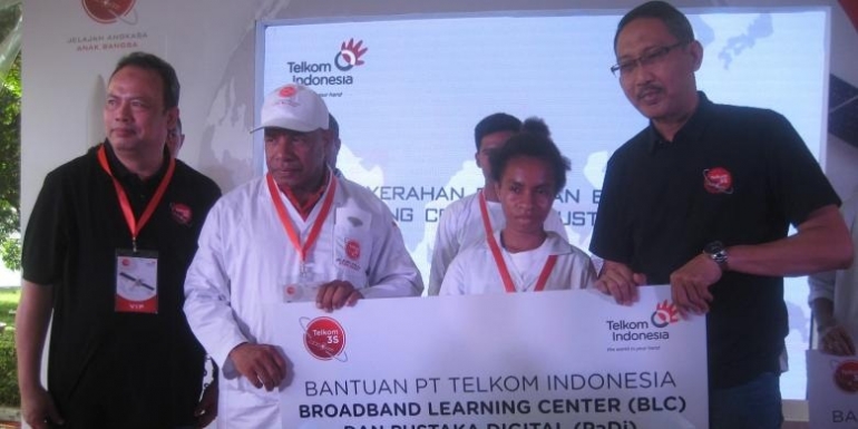 Direktur Network, IT & Solution Telkom Abdus Somad Arief (paling kanan) dan pejabat Telkom lainnya menyerahkan bantuan Broadband Learning Center (BLC) dan Pustaka Digital (PaDi) kepada Albertus (guru, kedua dari kiri) dan Laure (siswi, kedua dari kanan) dari SMA Negeri 9 Merauke sebagai perwakilan penerima bantuan dari wilayah 3T (Terluar, Terdepan, dan Terpencil) (Sumber: Kompas.com)