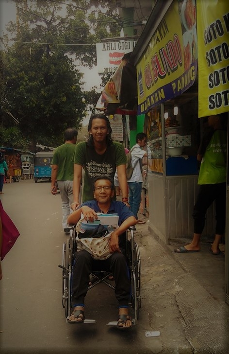 (Penulis, ketika sedang didorong di kursi roda oleh Bobbie TA / my son, di hari pertama keluar dari Rumah Sakit. Dan pagi-pagi bersiap-siap mengikuti Rehabilitasi Fisioterapi, menyusuri jalan Kota Bambu Selatan yang ramai dengan jualan aneka masakan khas tersebut. / Photo by: Dhinda AA Rendra)