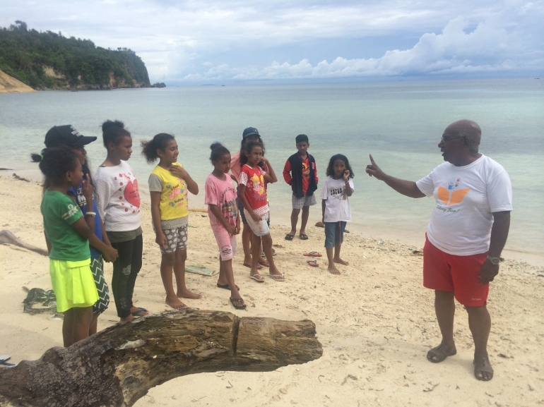 Bapak Isaskar sedang mengarahkan anak-anak untuk berani mengingatkan orang dewasa agar tidak buang sampah ke laut