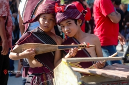 Anak kecil bermain Hasapi. Sumber gambar: https://pinouva.com/karnaval-kemerdekaan-ri-ajang-bagi-danau-toba-untuk-tebar-pesona/
