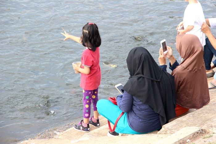 Senangnya anak-anak memberika makan ikan. (Foto: Gapey Sandy)