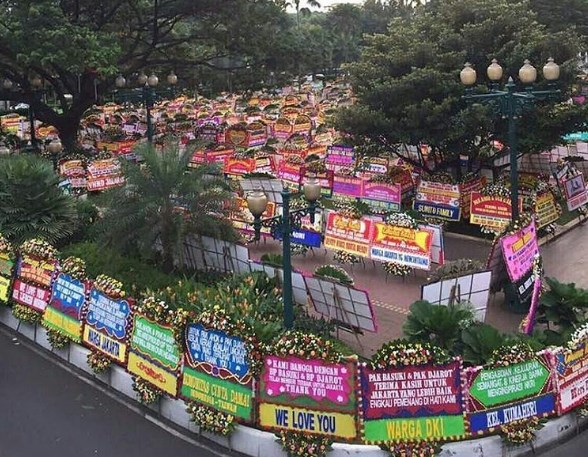 (Pemandangan yang unik, ketika Balai Kota kemudian dibanjiri oleh ribuan Bunga buat kandidat yang kalah. Fenomena sosial yang langka, yang mungkin hanya terjadi di Jakarta. Bahkan sampai ke Batam, medan dan Yogya segala yang penduduknya tidak ikut Pilkada DKI. Mungkin, nanti setelah dia dipenjara, LP Cipinangpun akan kebanjiran Bunga juga../ sumber photo: Suratkabar.id)