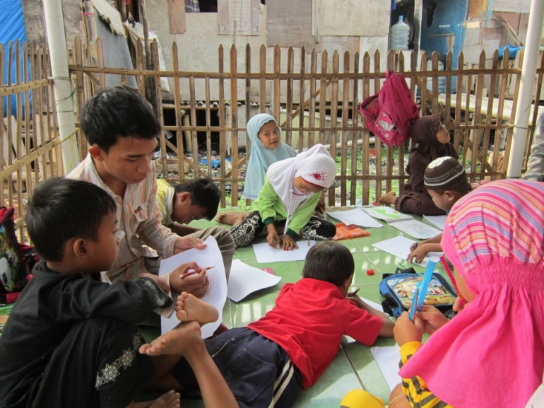 Supian sedang mengajar anak-anak Nelayan di kelas emperan Musholla