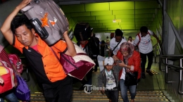 Seorang pemudik gratis menggunakan kereta api memanggul koper. Foto: Tribunnews.com