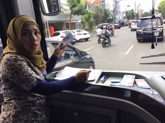 Pramugari bus pariwisata, Diah tengah mengecek tiket gratis yang dibagikan kepada penumpang (Foto: Dokpri)