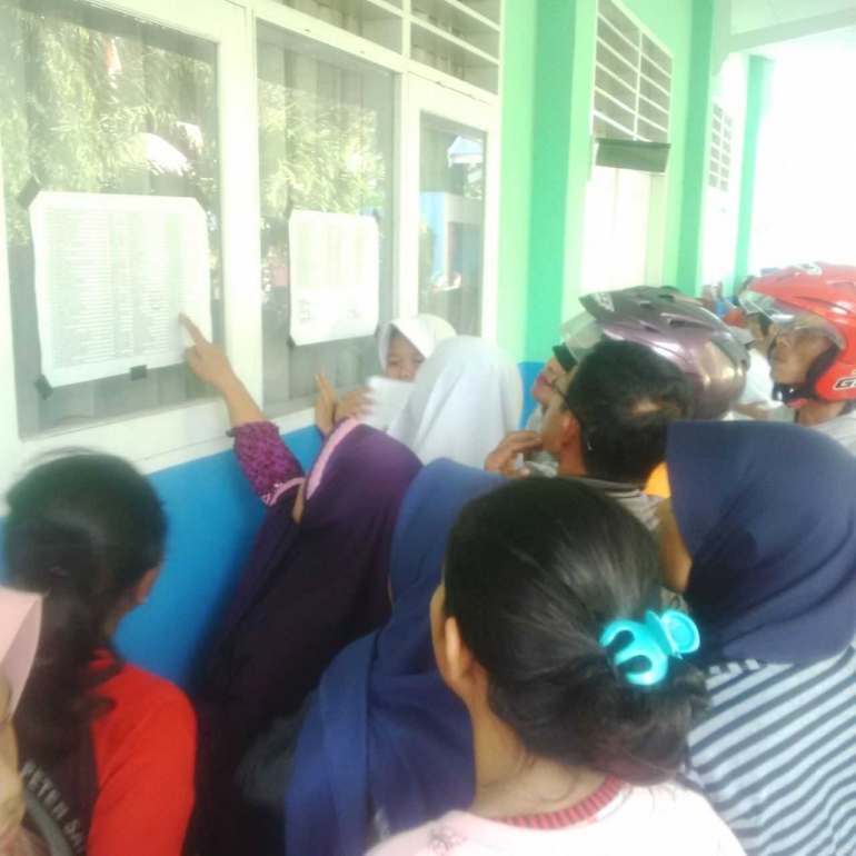 ORANGTUA siswa melihat pengumuman PPDB di SMPN 15 Palu, Senin (10/7/2017). FOTO : RAFIQ 