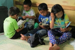 Anak- anak tengah menyimak buku di base camp (foto: dok PG)