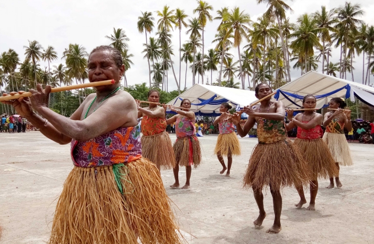 Mama-mama saat meniup suling dengan nyanyian khas Raja Ampat