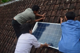 Warga bersama mahasiswa memasang solar cell di atas rumah warga. Foto: Eka Maulana/UB.