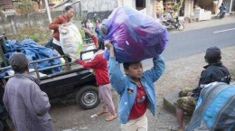 Seorang bocah membawa barang dari pikap ke lokasi pengungsian Gunung Agung di Bali. FOTO: CNN Indonesia.