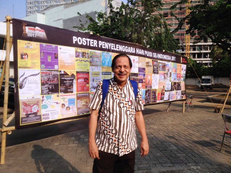 Berfoto di depan poster-poster penyelenggaraan Hari Puisi di berbagai daerah di Indonesia. (Foto; R. Andi Widjanarko, ISJ)