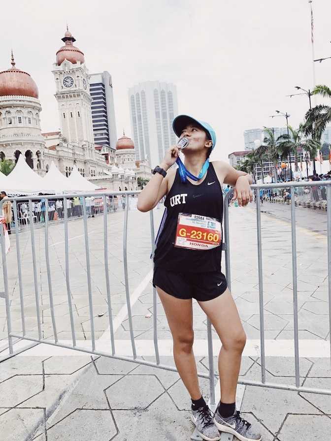 Editha mencium medali setelah menempuh half marathon race di Kuala Lumpur, 2017. (foto: dok.Editha)