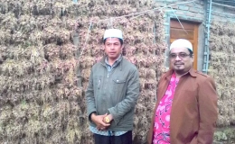 USTAZ H. Khaidir Jumin dan Samsudin, pembimbing ibadah petani Bawang Sungainanam diabadikan dengan latar belakang bawang yang dijemur sesudah panen. (DOK. PRIBADI)