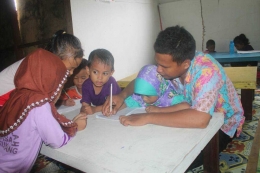 Pak Salim sedang mengajar menulis anak-anak pekerja migran Indonesia di perkebunan Sarawak. Foto: Dok. Pribadi.