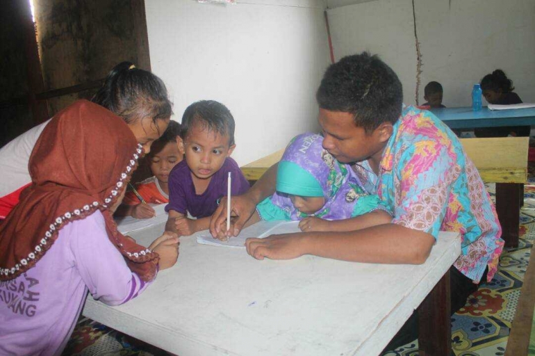 Pak Salim sedang mengajar menulis anak-anak pekerja migran Indonesia di perkebunan Sarawak. Foto: Dok. Pribadi.