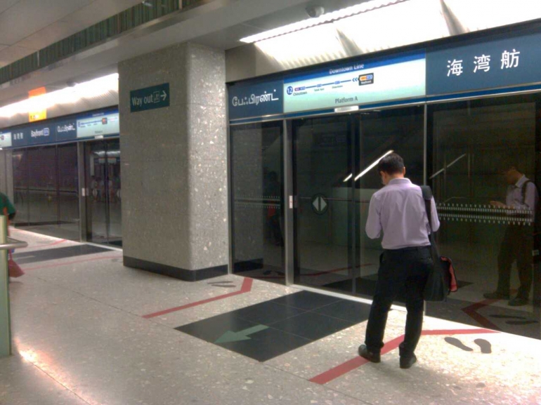 Seorang penumpang sedang menunggu MRT. Terlihat garis pembatas berwarna merah antara pintu masuk (dok pribadi)