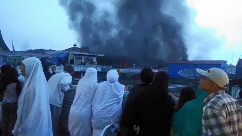 Warga Bukittinggi yang baru saja selesai melaksanakan Salat Subuh memandang asap hitam membumbung dari Pasar Aur Kuning yang terbakar, Jumat (17/11/2017). (FOTO: REPRO KORAN PADANG)