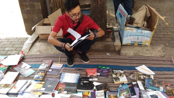 Rendy Kurniawan sedang membaca buku saat lapak buku di halaman gereja GKI Kebonagung seusai ibadah. Dokumentasi perpustakaan Eklesia.