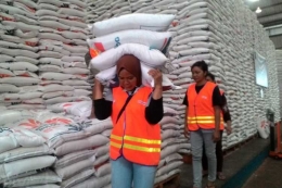 Aktifitas buruh wanita dapat memikul empat karung beras di gudang Bulog Panaikang, Makassar, Jumat (12/1/2018).(KOMPAS.com/Hendra Cipto)