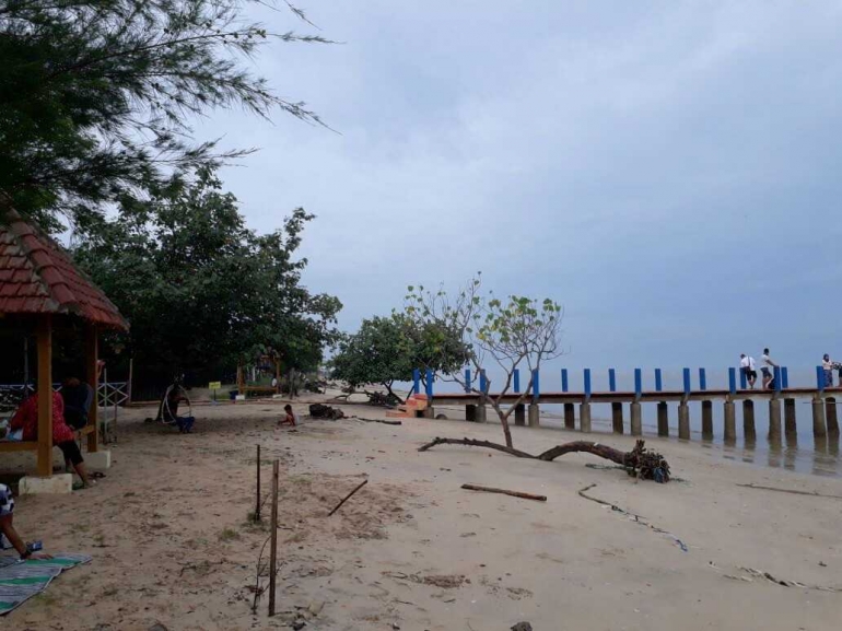 Kayu kering yang dibiarkan teronggok di tepi pantai, memberi kesan alami. (Dokpri).