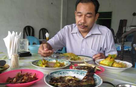 MENIKMATI IKAN SUNGAI: Penulis menikmati ikan sungai di sebuah warung di Kuala, Langkat, Sumut. Foto/M.Fachriz Tanjung