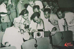 Wartawan peliput KAA 1955 sibuk melakukan wawancara. (Foto: Repro Frino Bariarcianur)