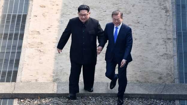 Kim Jong Un bergandengan tangan dengan Presiden Korea Selatan Moon Jae-in ketika melangkah ke tanah Korea Selatan. Photo: Getty Images
